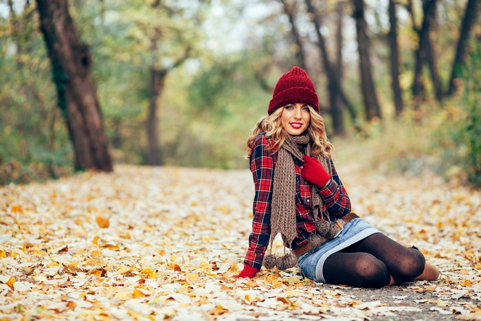 Woman in autumn park wearing winter hat and scarf