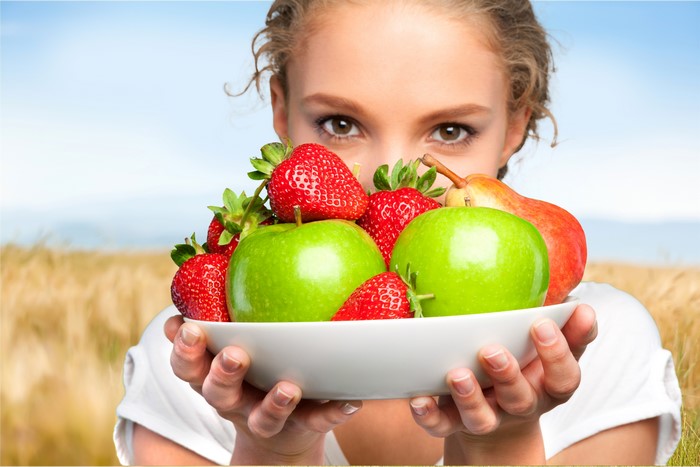 Woman holding a bowl of apples and strawberries