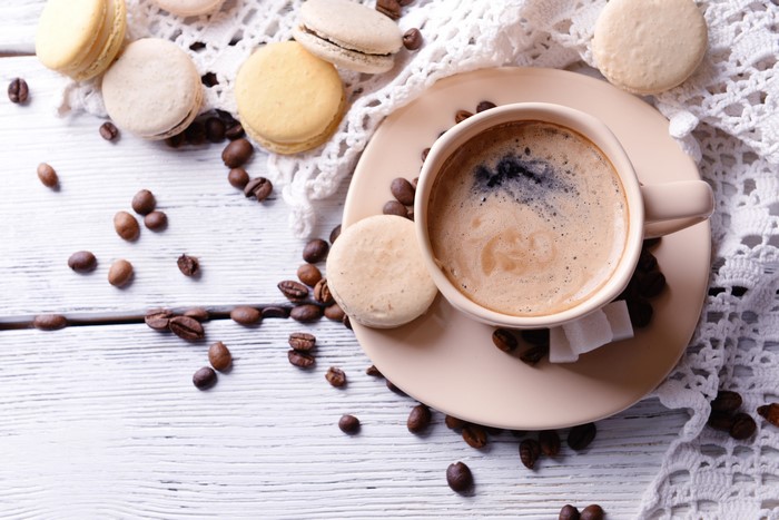 Coffee cup with macarons and coffee beans