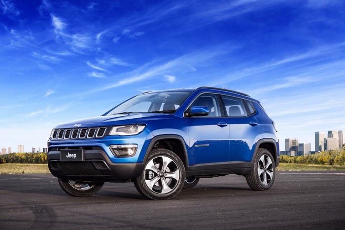 Blue Jeep Compass on a Road with City Skyline