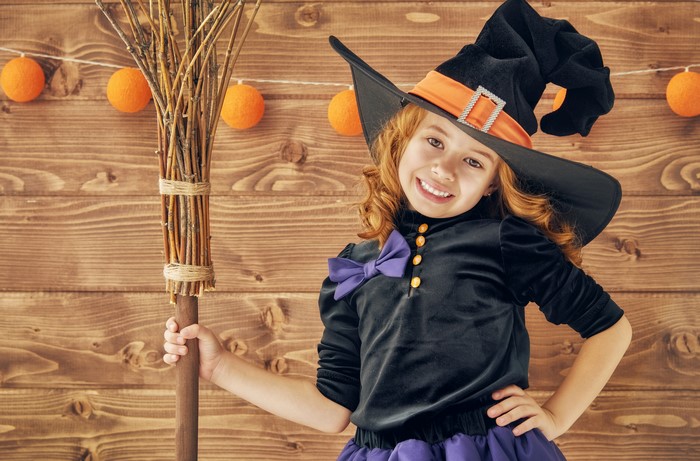 Girl in Witch Costume with Broomstick and Halloween Decorations