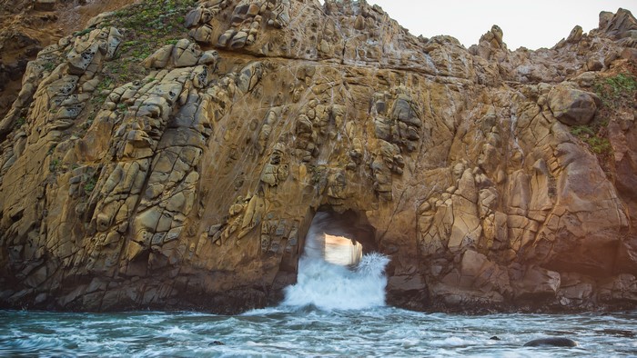 Wave crashing through rock archway