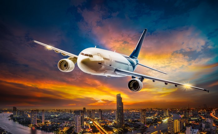 Airplane flying over a city at sunset
