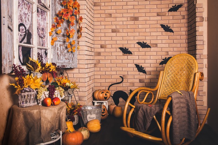 Halloween decor with pumpkins, apples, grapes, and rocking chair