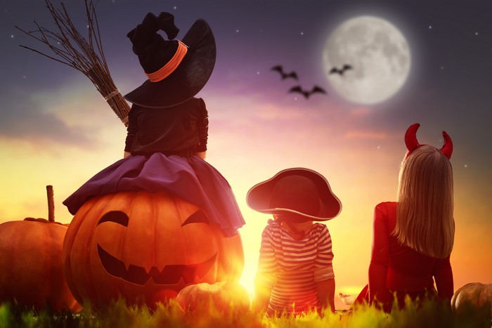 Children in Halloween costumes on a pumpkin patch at night