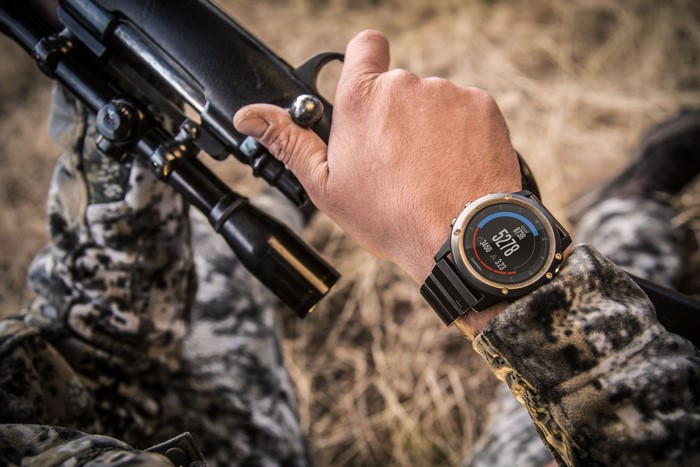Man wearing Garmin watch holding a rifle