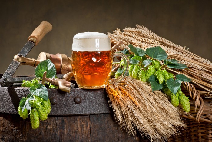 Beer mug with hops and wheat on a barrel