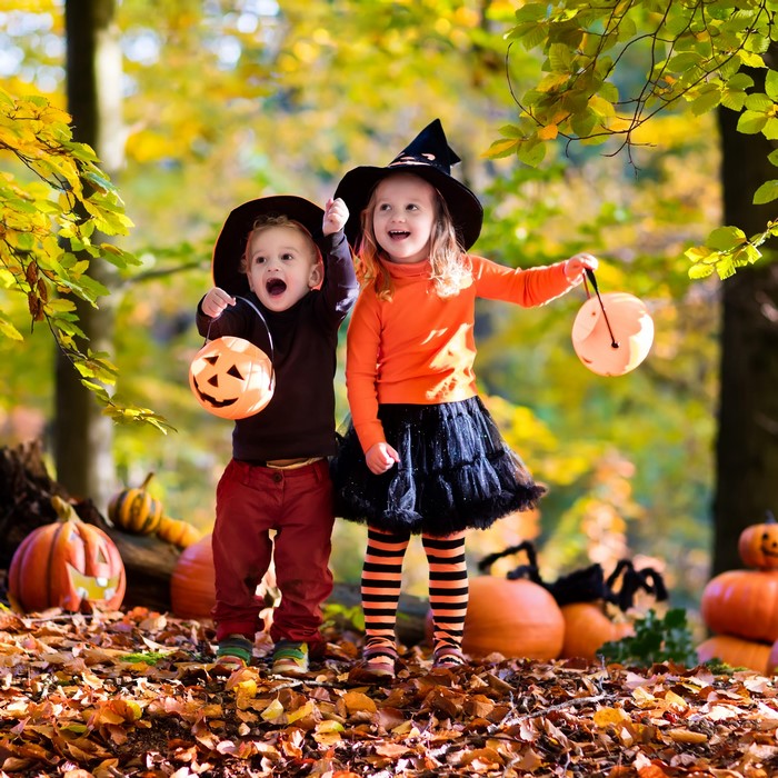 Two children in Halloween costumes with pumpkins