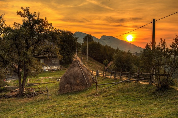 Sunset over a Romanian village with haystacks