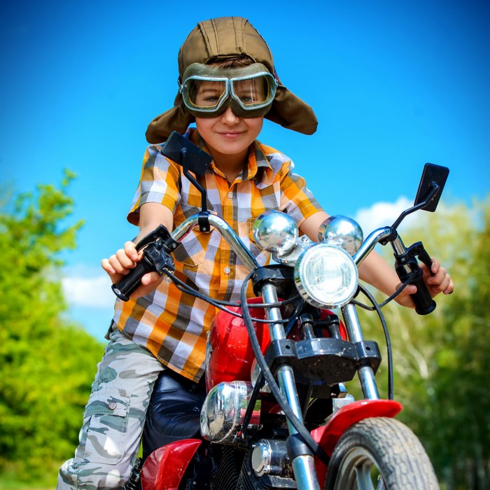 Boy in pilot helmet and goggles on a motorcycle
