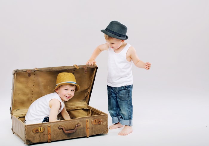 Two boys with hats and a suitcase