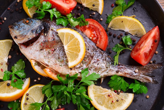 Whole baked fish with lemon, tomato, and herbs