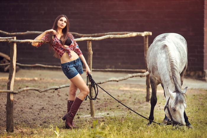 Woman in plaid shirt and shorts with horse