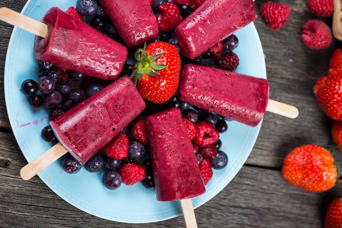 Berry popsicles on a plate with fresh berries