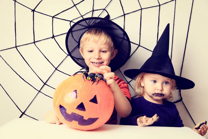 Two children in Halloween costumes with a pumpkin