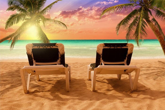Two sun loungers on a tropical beach at sunset