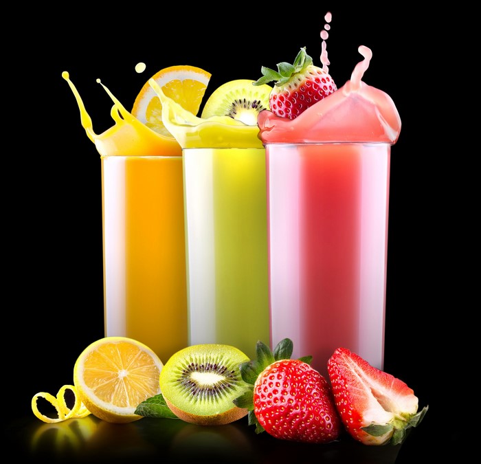 Three glasses of juice with fruits and splashes