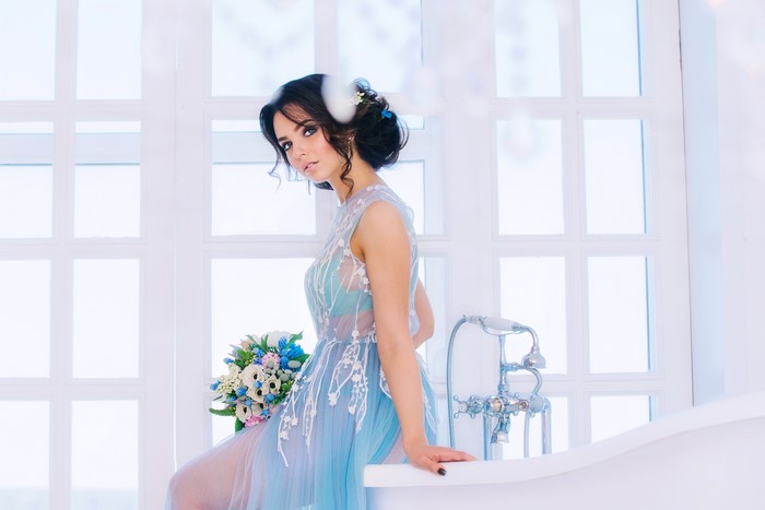 Brunette girl in a blue dress with a bouquet