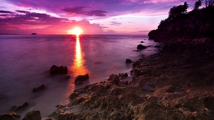 Sunset over the ocean with rocky shore