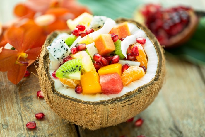 Fruit salad in a coconut shell with pomegranate and orchids