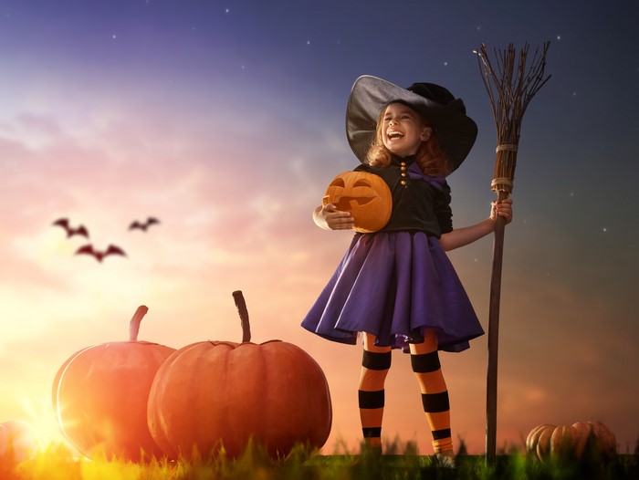 Girl in Witch Costume with Pumpkin and Broom
