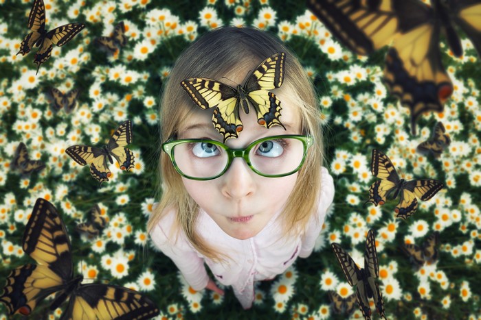 Girl with glasses surrounded by butterflies