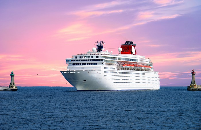 Cruise liner sailing between lighthouses at sunset