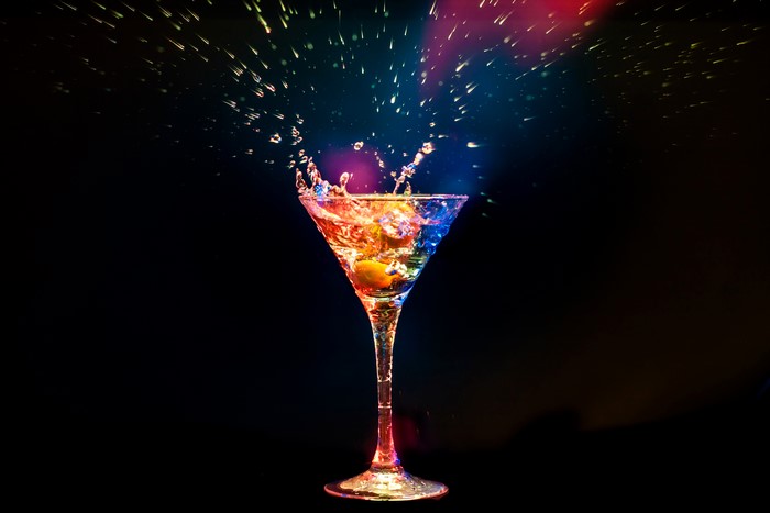 Cocktail with water splash and colorful lights