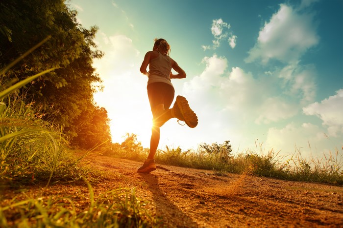 Woman running on a dirt path at sunset