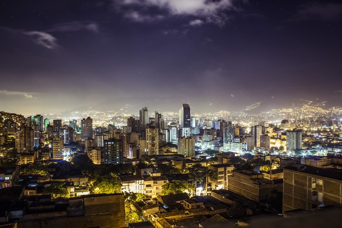 Nighttime cityscape of Medellin, Colombia with distant mountains