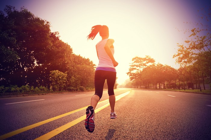 Woman running on road during sunrise