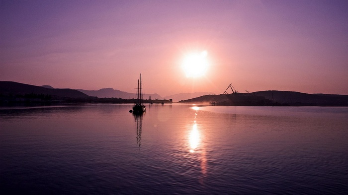 Sailboat on a calm sea at sunset with mountains