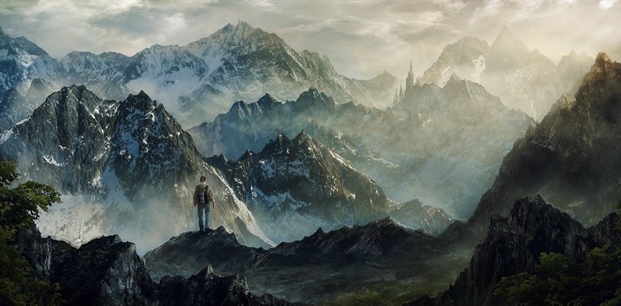 Man standing on mountain peak overlooking misty mountain range with castle