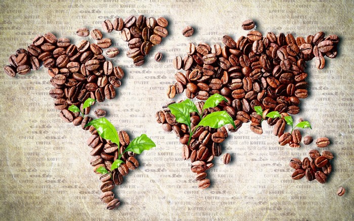 World map made of coffee beans with green leaves