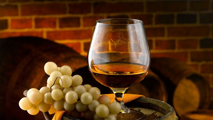 4K Brandy in a snifter glass with grapes and barrels