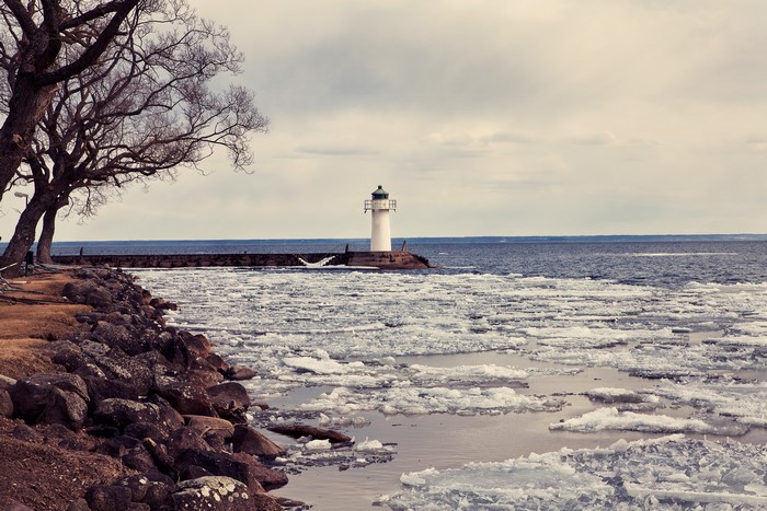 Lighthouse on a pier with ice on the water