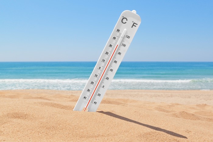 Thermometer on a sandy beach with the ocean in the background