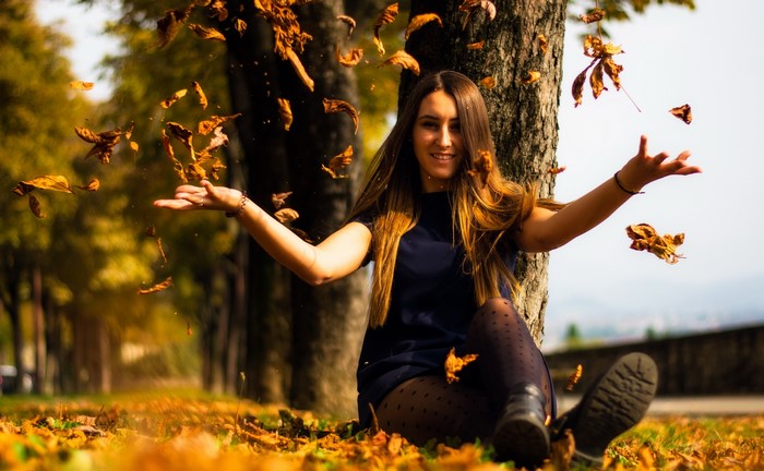 Young woman sitting in autumn leaves
