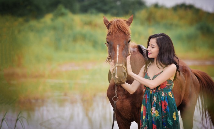 Asian woman with horse near water