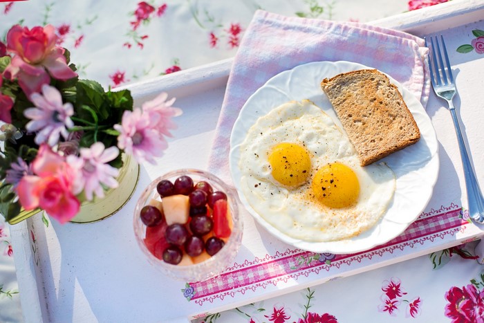 Breakfast with fried eggs, toast, fruit, and flowers