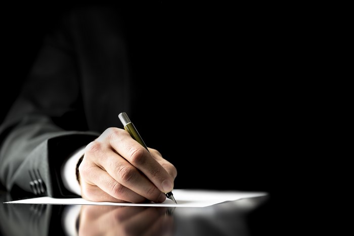 Man in Suit Writing with Pen on Paper