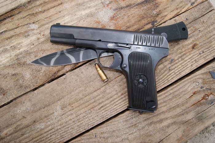 Pistol and Knife with Ammunition on Wood Planks