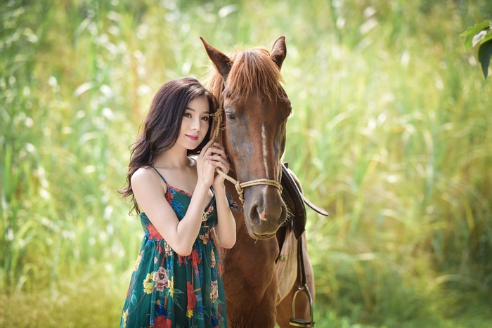 Asian woman with horse in a field
