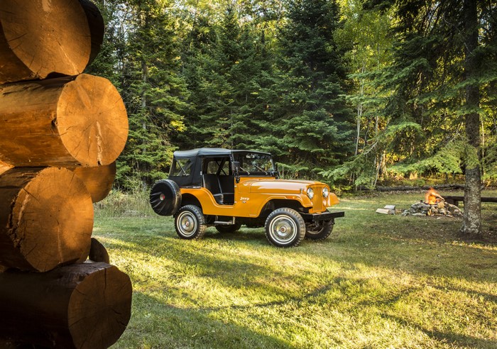 Orange Jeep CJ-5 in a forest clearing