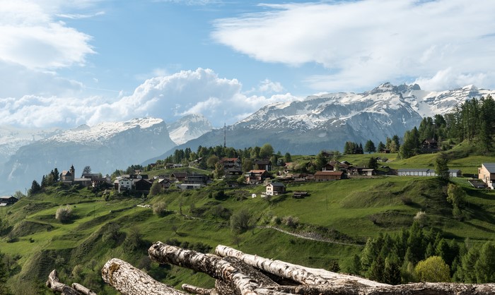 Houses on a hillside in the Swiss Alps with snow-capped mountains