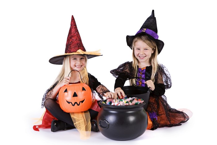 Two young girls in witch costumes with Halloween candy