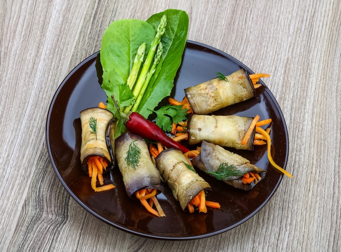 Eggplant rolls with carrots and asparagus on a plate