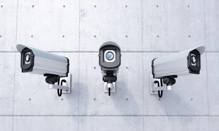Three security cameras on a concrete wall