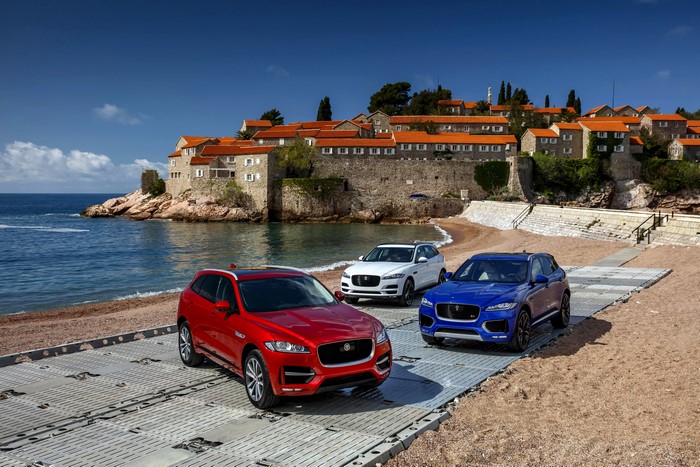 Three Jaguar F-Pace SUVs on a Beach with a Coastal Town