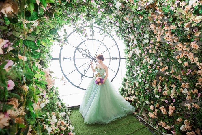 Asian woman in a green dress in front of a clock